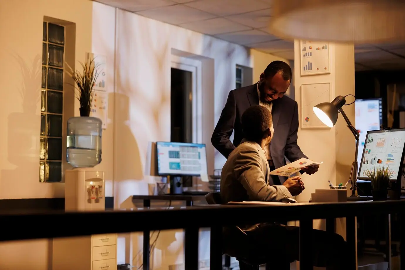 Unternehmer betrachten einen Bericht über das finanzielle Wachstum und besprechen eine Investitionsstrategie zur Steigerung des Unternehmensgewinns. Unternehmensangestellte arbeiten spät in der Nacht im Büro eines Start-ups an einem Managementprojekt.