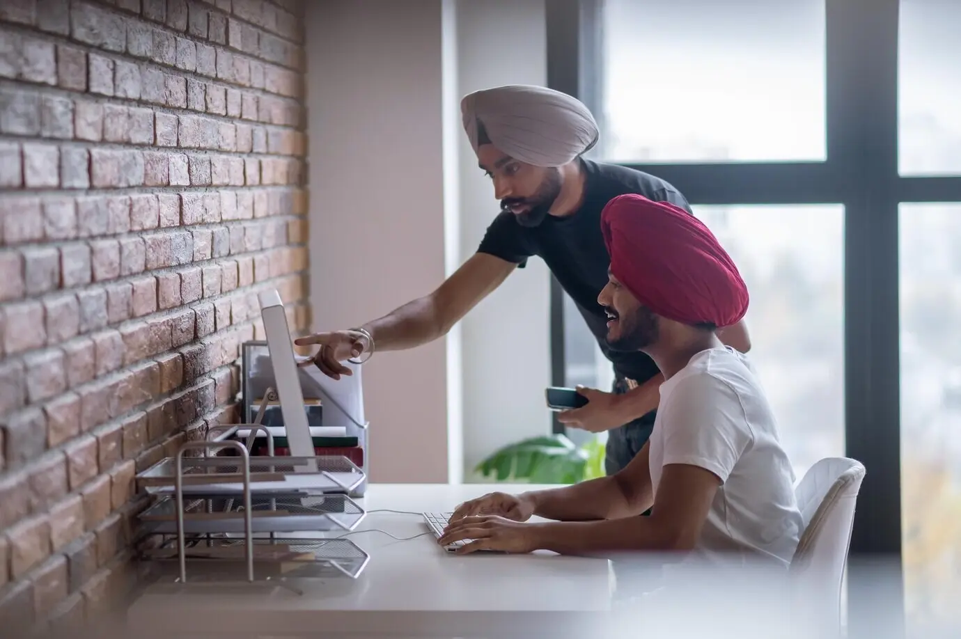 Arbeitstag. Zwei indische Männer besprechen etwas und wirken involviert.